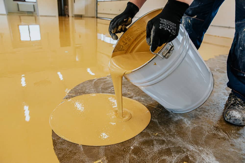 Crew pouring and spreading a fresh coat on a concrete floor